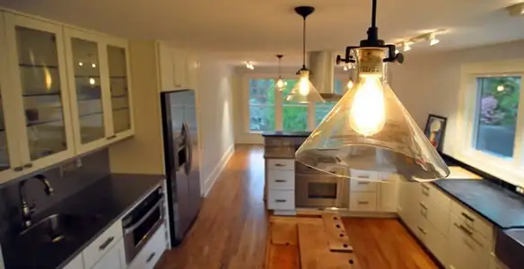 Residential electrician installing modern indoor light fixture in a home in Naperville, IL